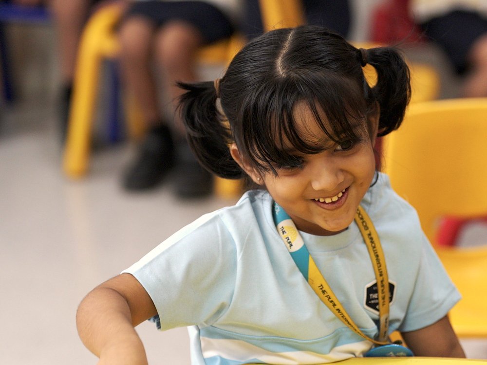 A girl smiling as she works at her table.