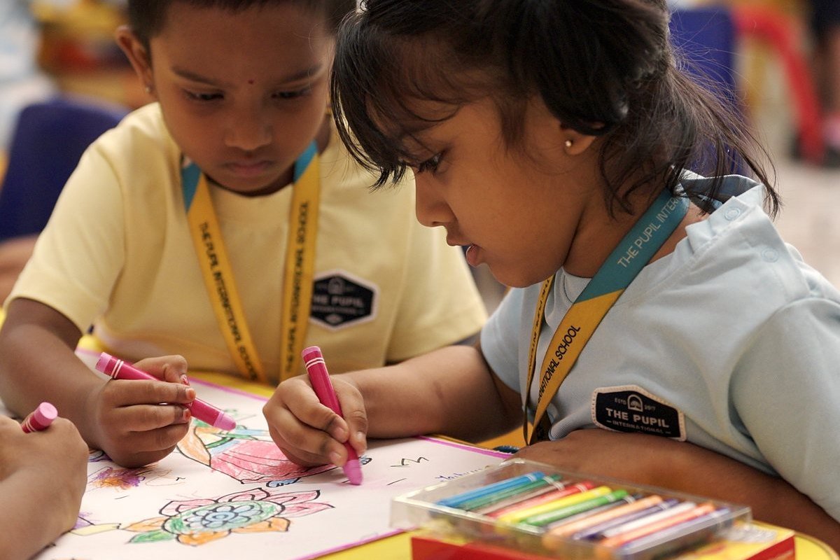 Two children colouring a picture together.