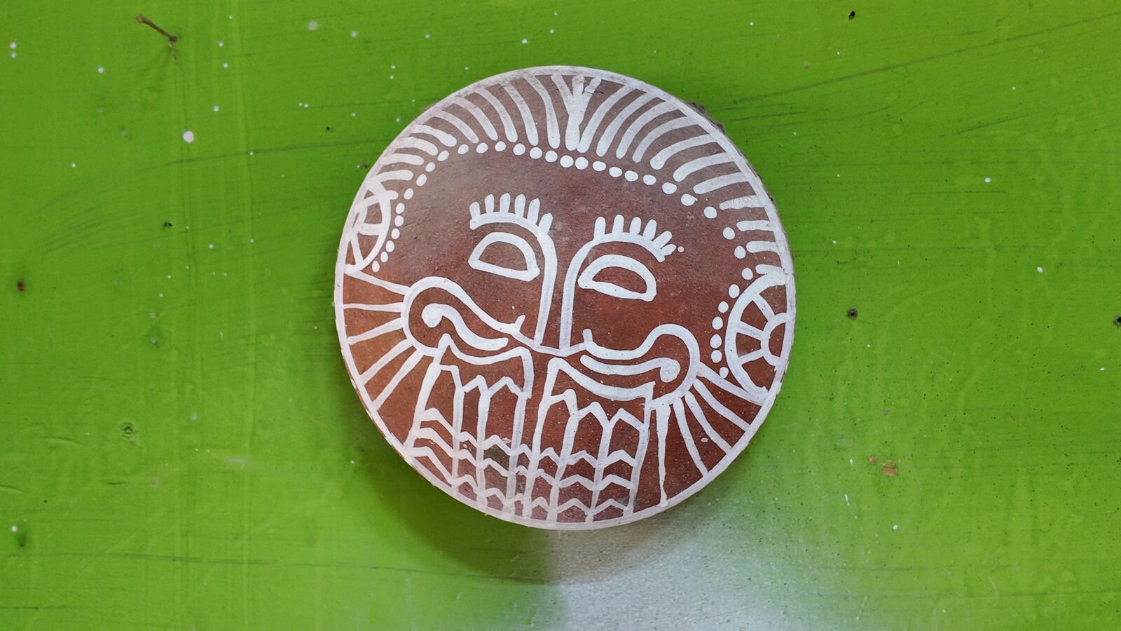 A terracotta plate with a face scratched through white slip.