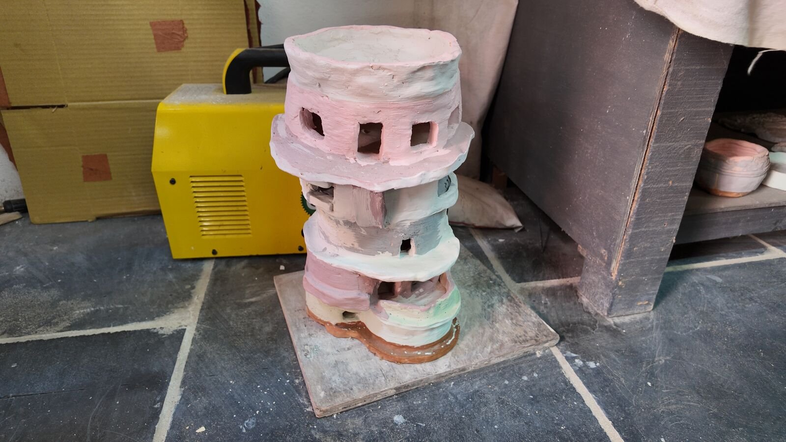 A tall hand-built clay tower with cut-out windows.