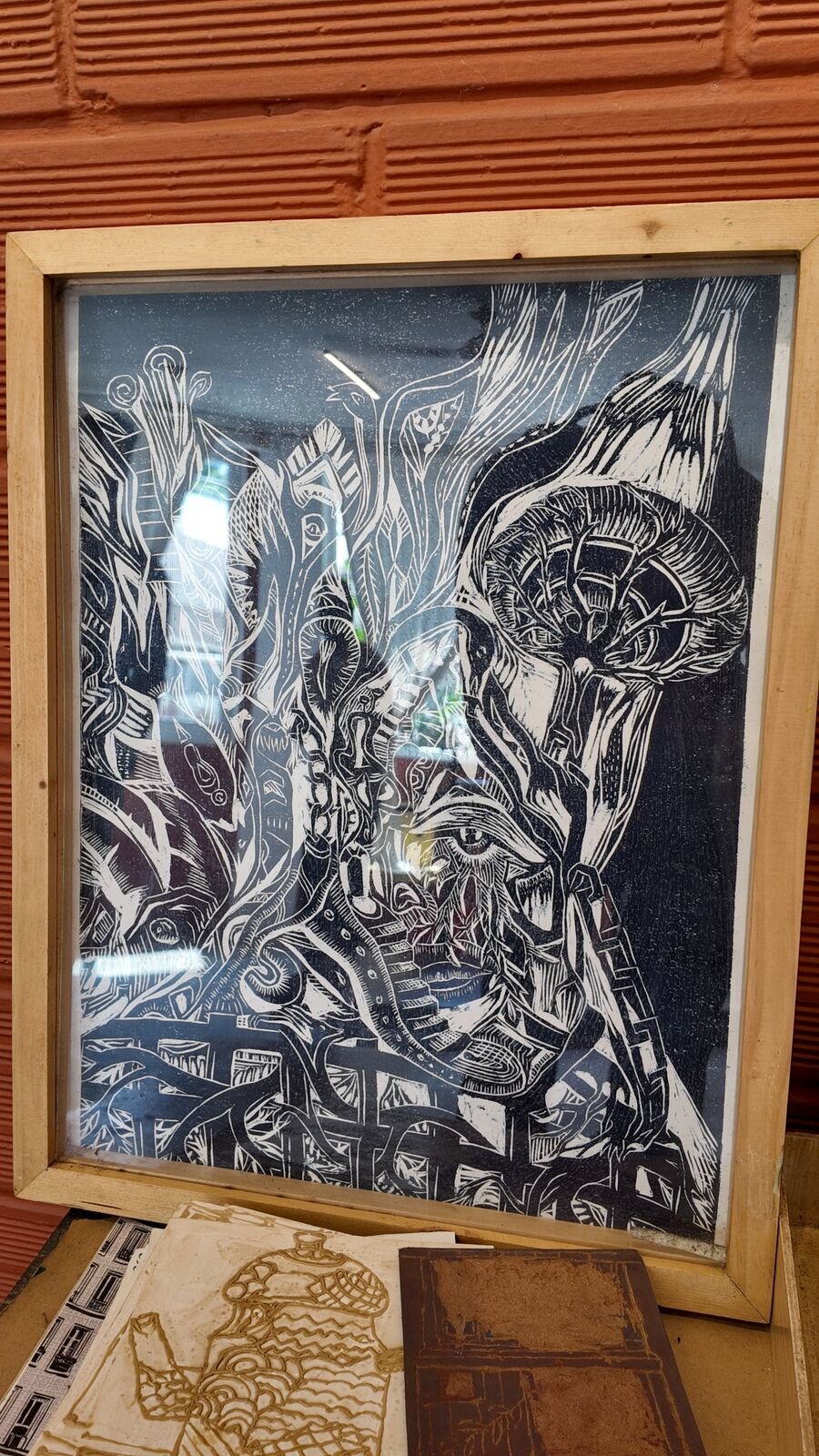 A detailed black and white lino print in a wooden frame.