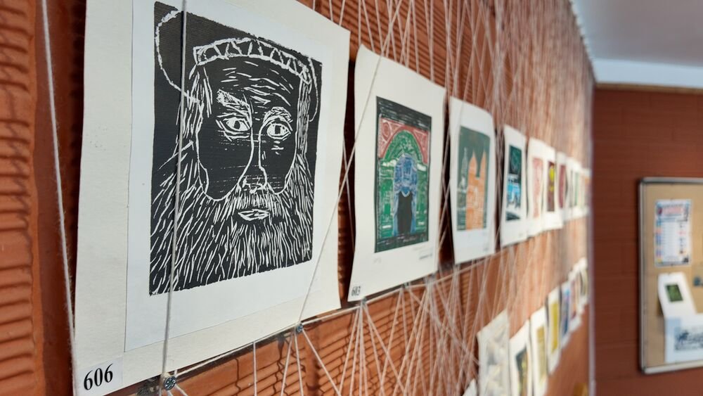 Lino-cut portraits hung along a studio wall.