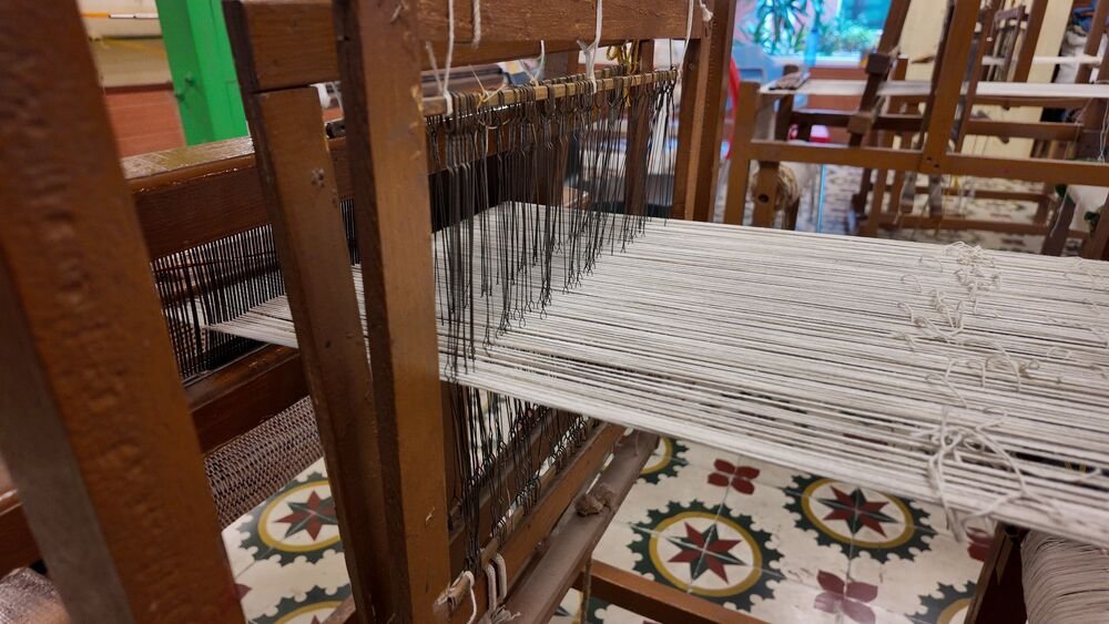 Threads set up on a wooden handloom in the weaving studio.
