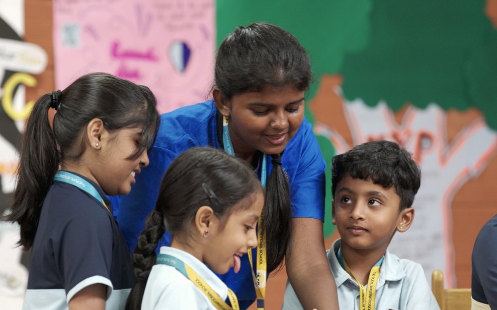 An older student laughing with three younger children.