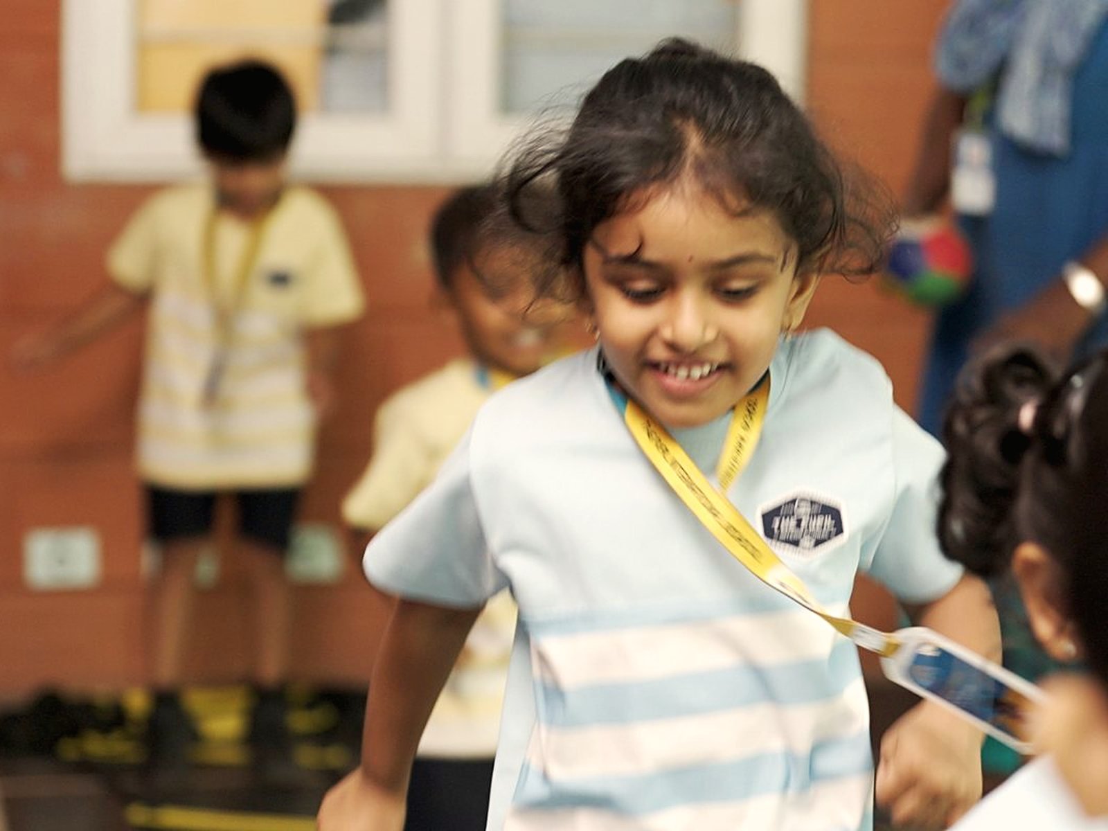 A young girl running and jumping, with friends behind her.