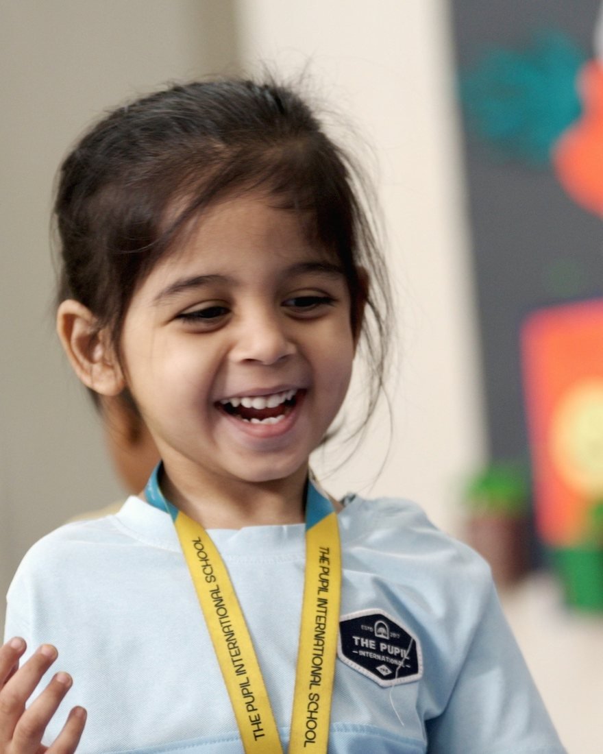 A young girl laughing in her Early Years classroom.