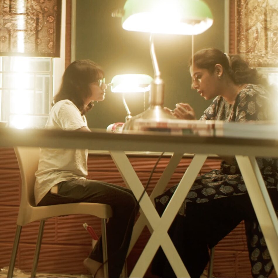 Two students studying at a lamp-lit table in the study hall.