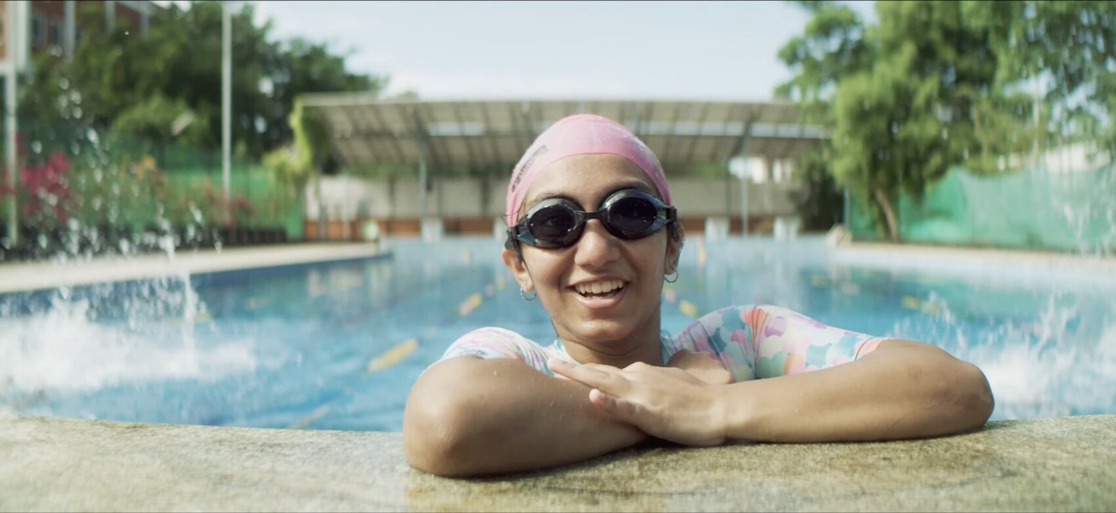 A student smiling at the edge of the swimming pool.