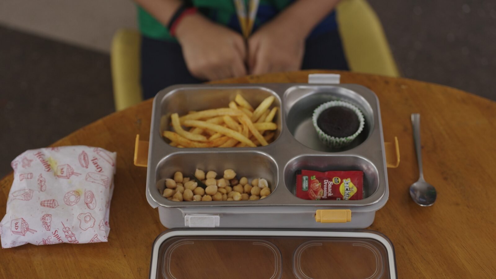 A bento box lunch with fries, chickpeas and a chocolate muffin.
