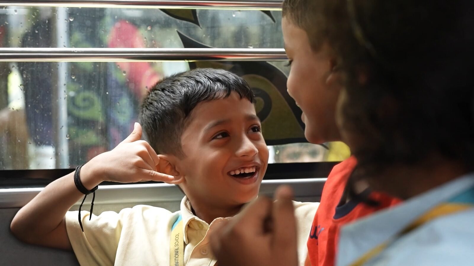 A boy laughing with a friend on the school bus.