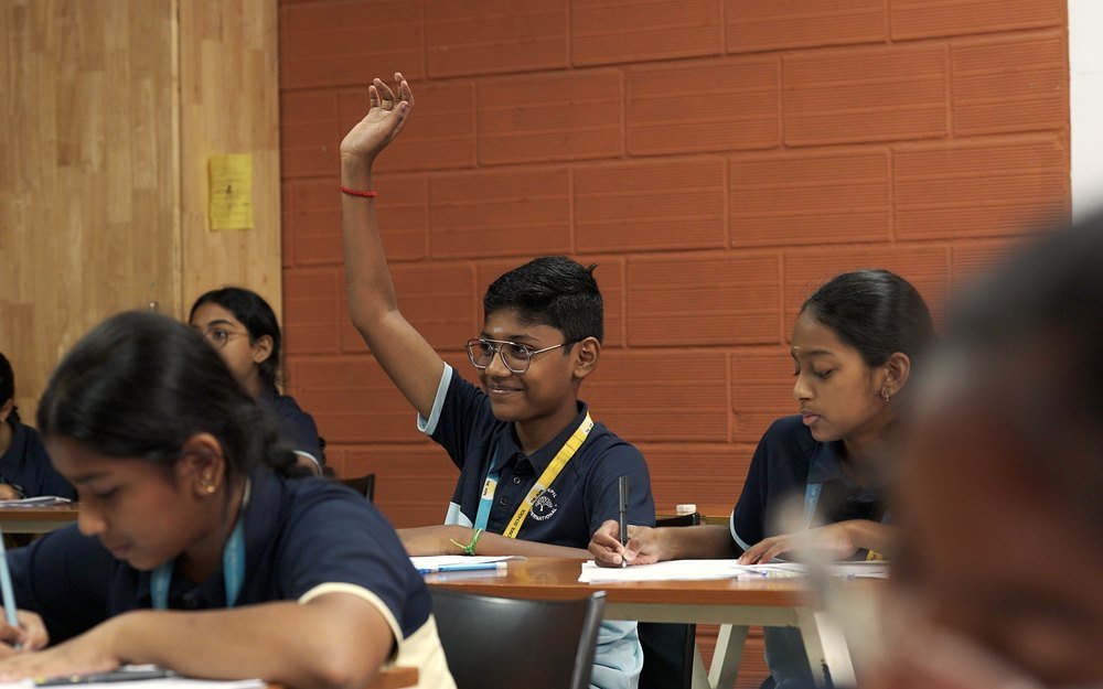 A student raising his hand to answer a question.