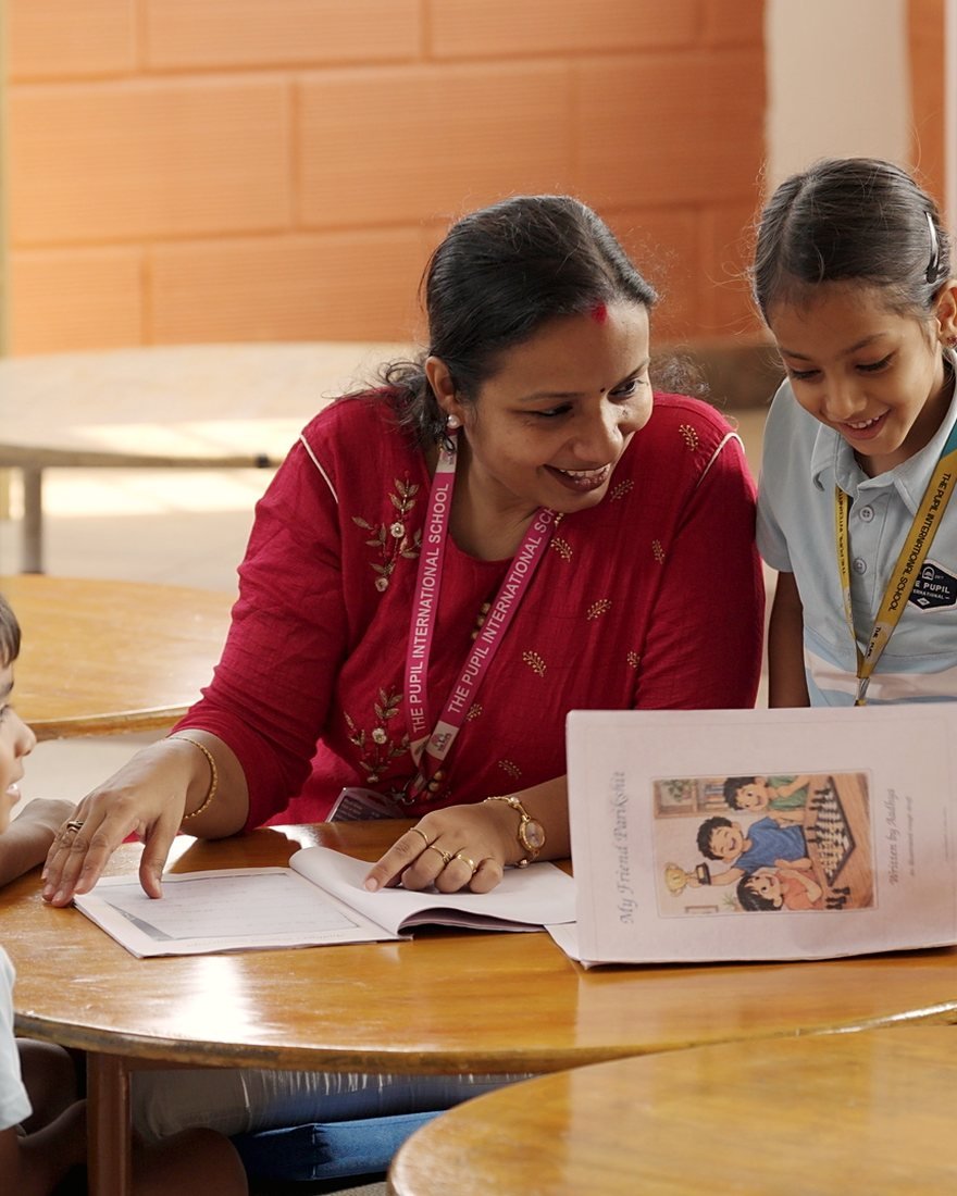 A teacher and a girl looking over her work together.