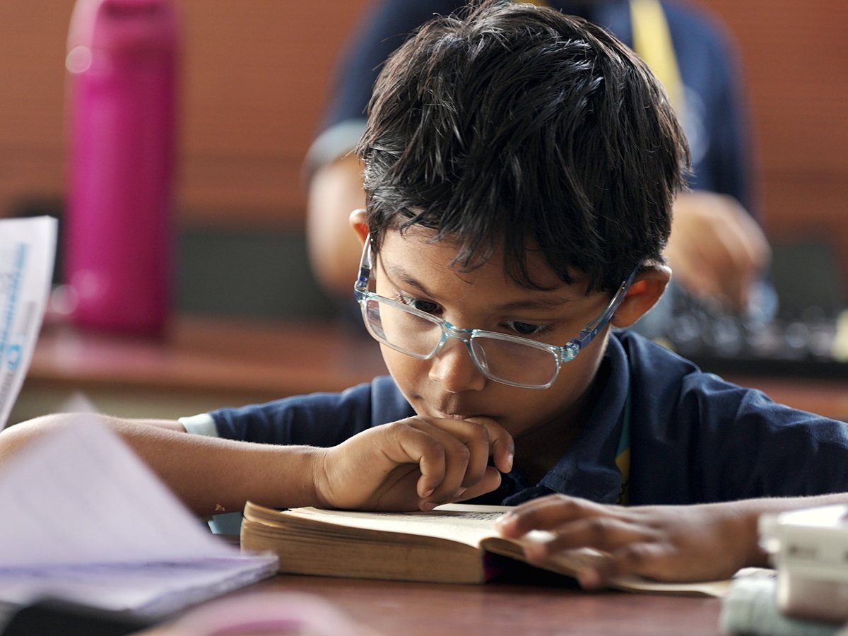 A boy reading a book at his desk.