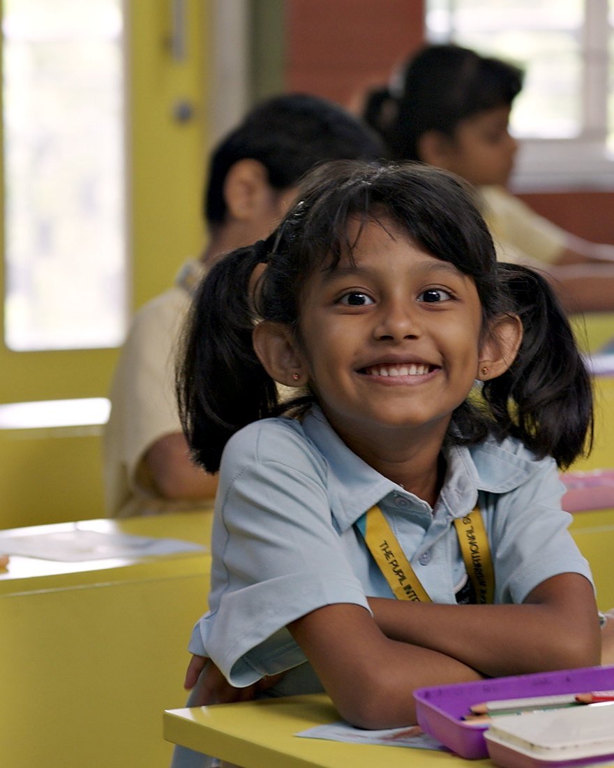 A girl smiling at her desk in her Primary Years classroom.