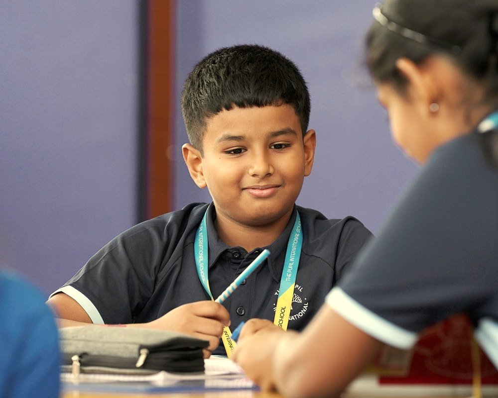 A Primary Years student smiling at his desk.