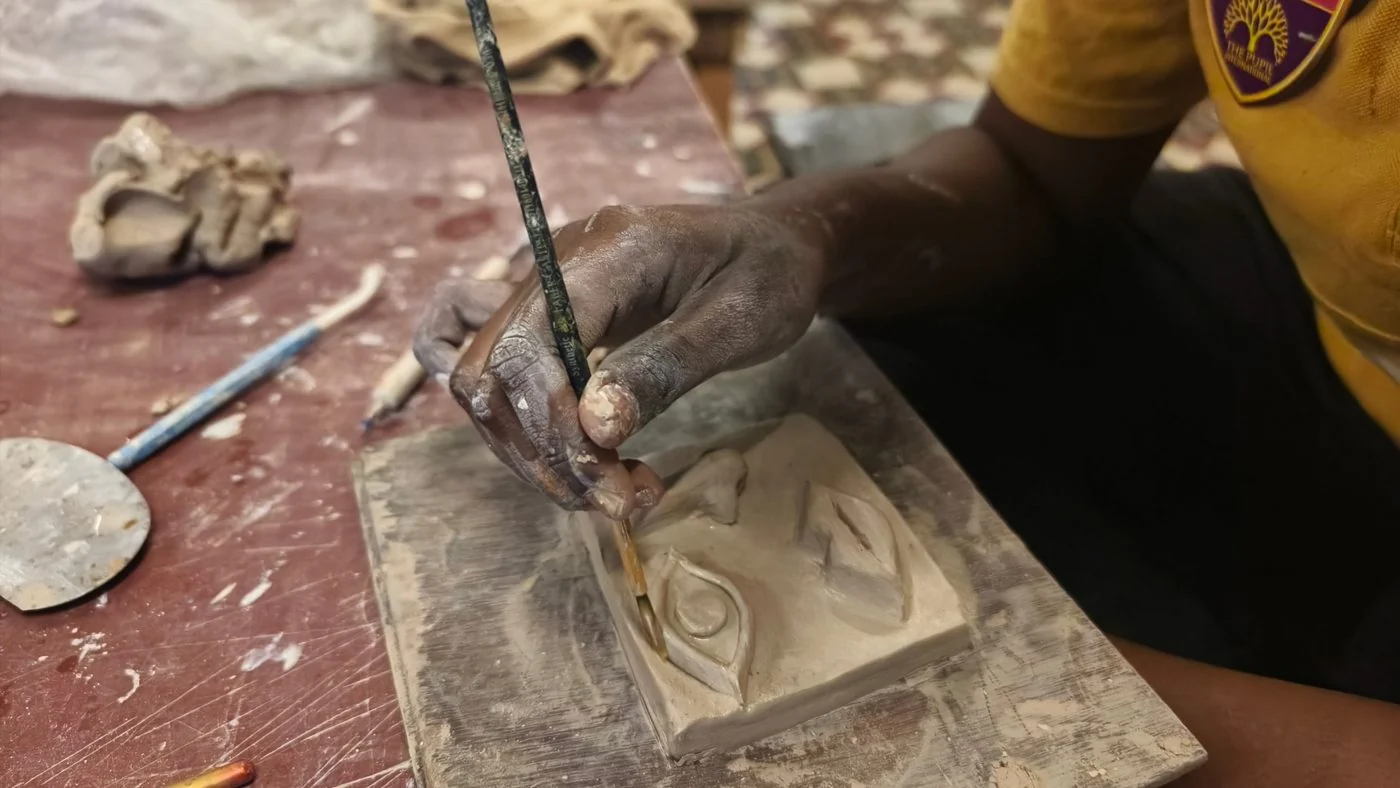 A student working an eye into a clay relief tile.