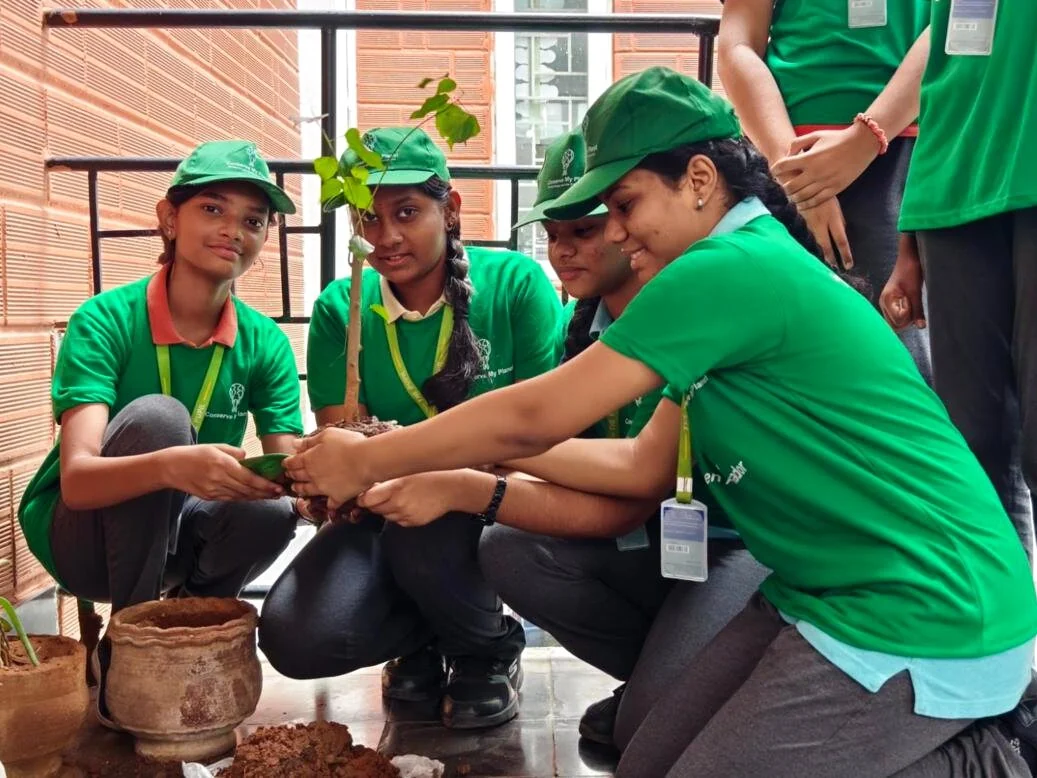 Eco Warriors students planting a sapling together and smiling.
