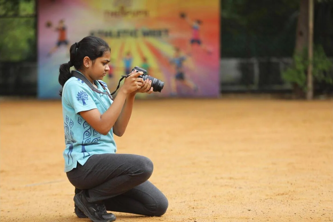 A Photography Club student kneeling to frame a shot.