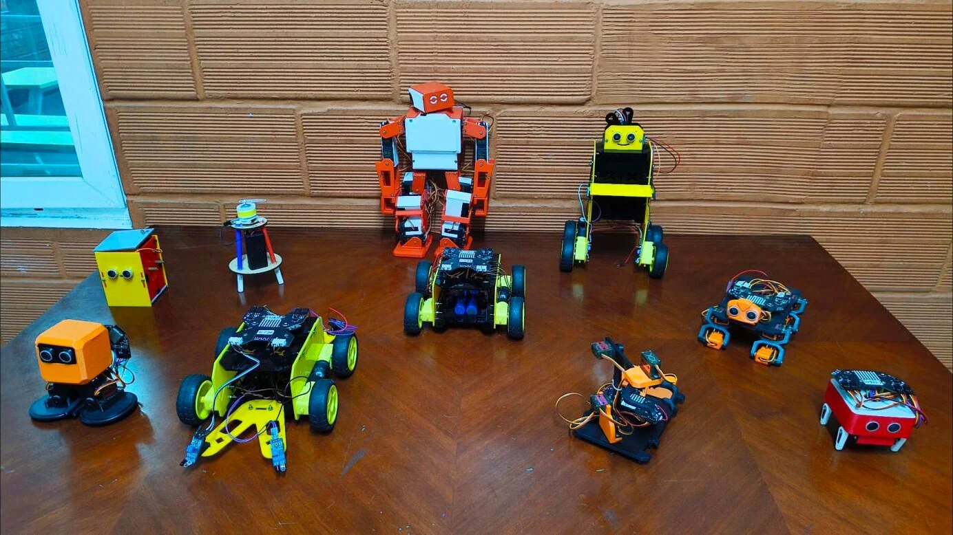 Robots built by Robotics Club students, including a walking humanoid and wheeled rovers.