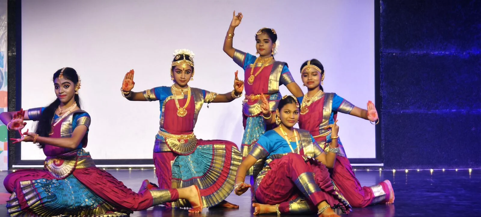 Bharatanatyam dancers in costume striking a pose together.