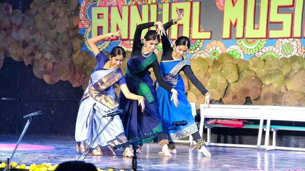 Three dancers performing a classical dance on stage.