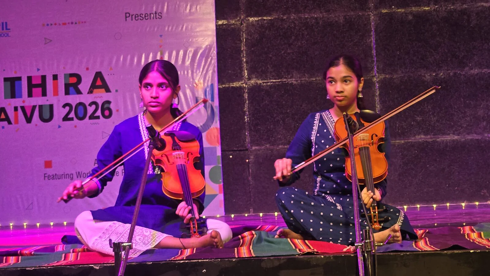 Two students playing violin on stage.