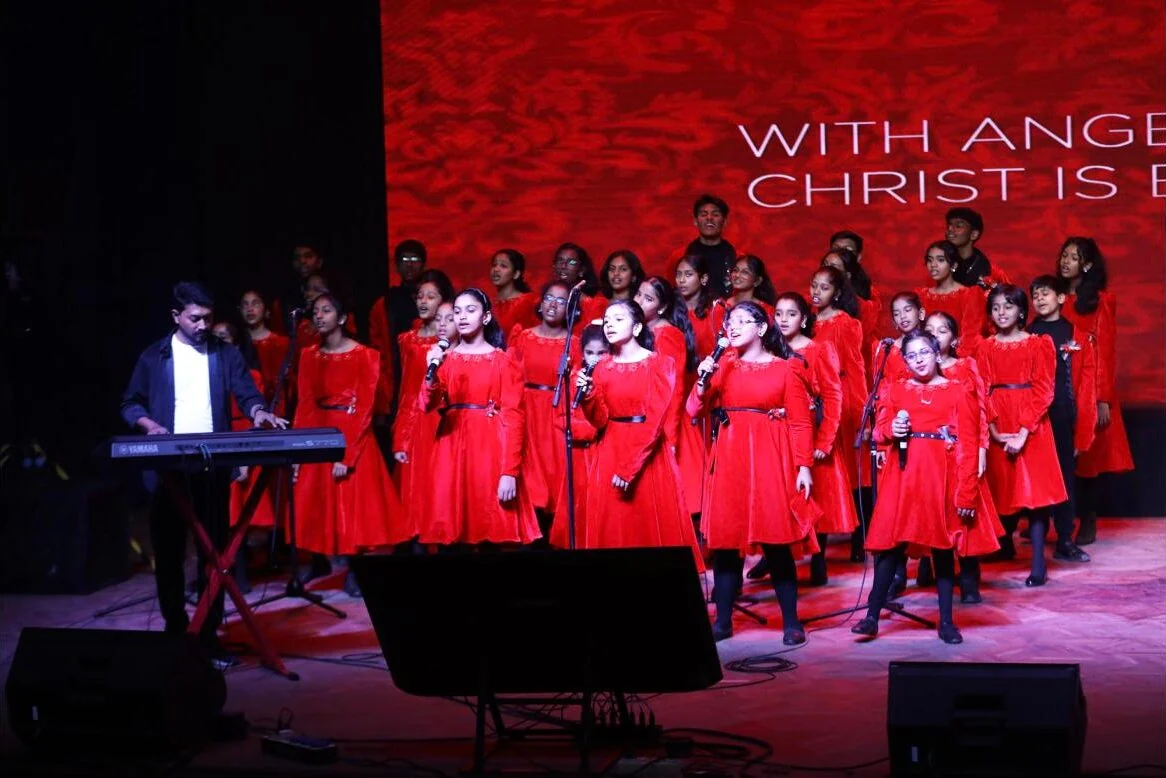 The student choir in red singing carols on stage.