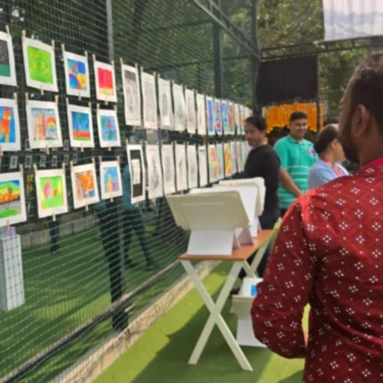 Student paintings pegged along the exhibition wall.