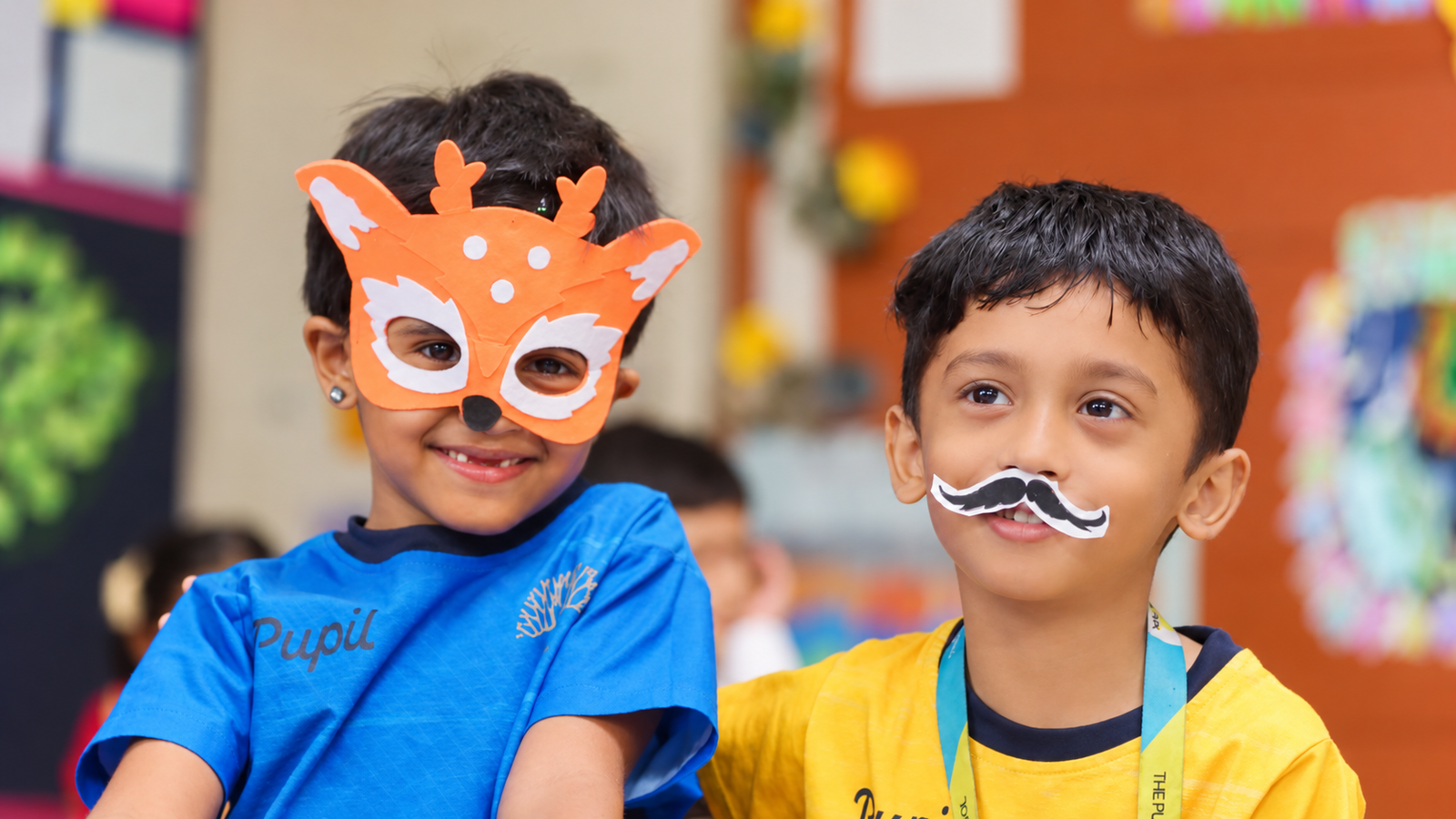 Two children wearing a handmade deer mask and paper moustache at The Pupil International School, Chennai.