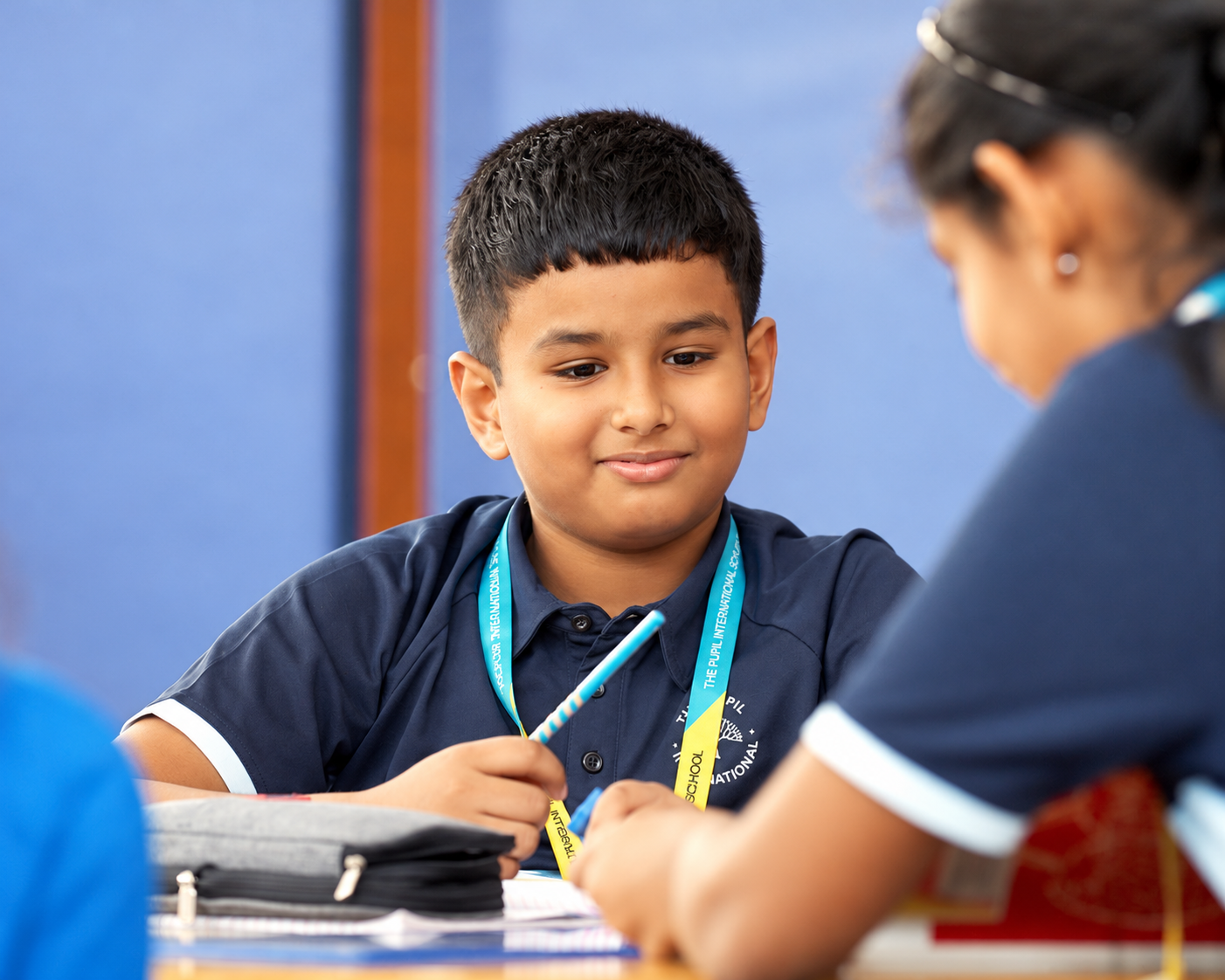 classroom-learning.png Student holding a pencil beside classmates at The Pupil International School, Chennai.