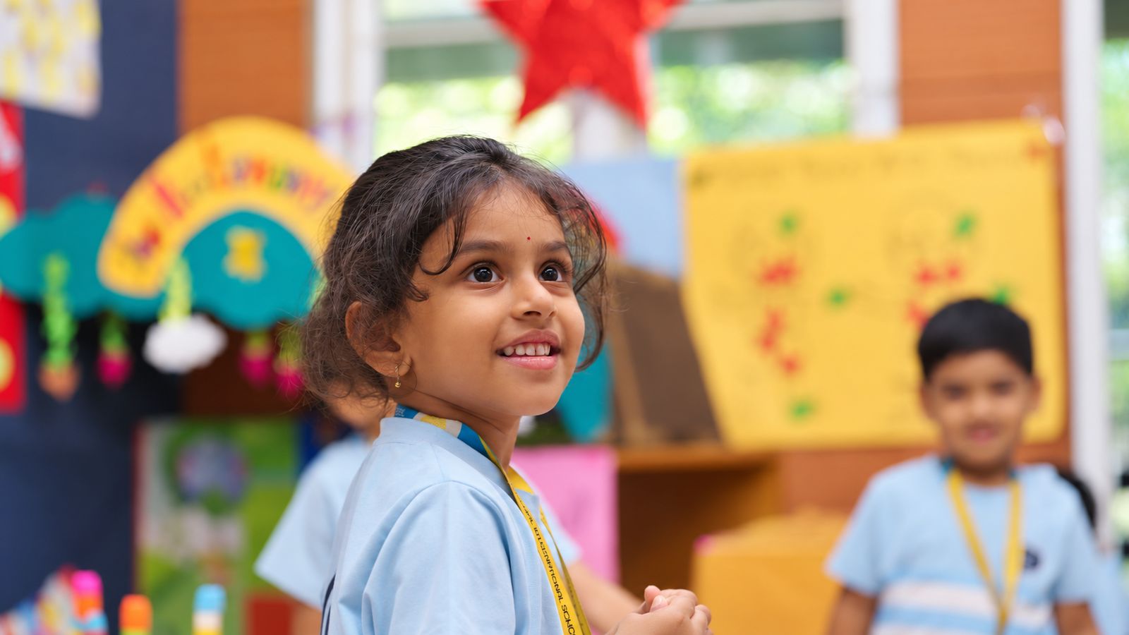 Young student smiling and looking upwards during a classroom activity at The Pupil International School, Chennai.