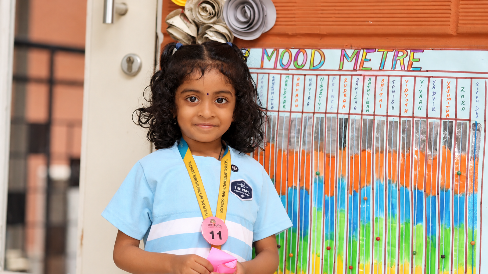 Early years student beside a colourful mood meter at The Pupil International School, Chennai.