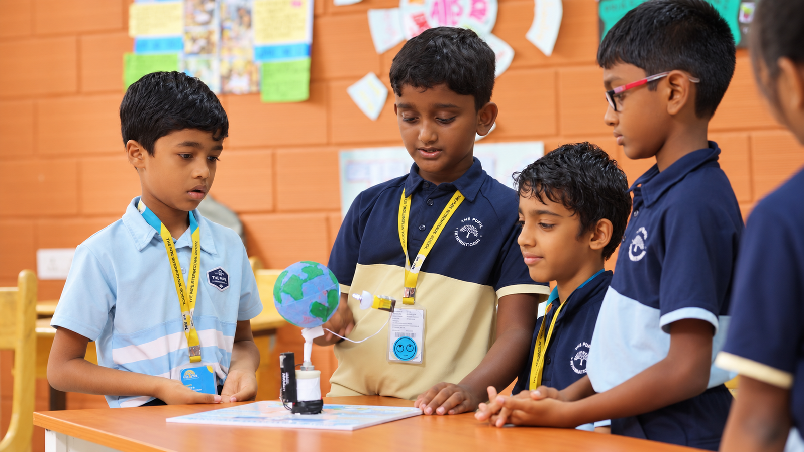 Students examining a globe model with a small light bulb during a science activity at The Pupil International School.