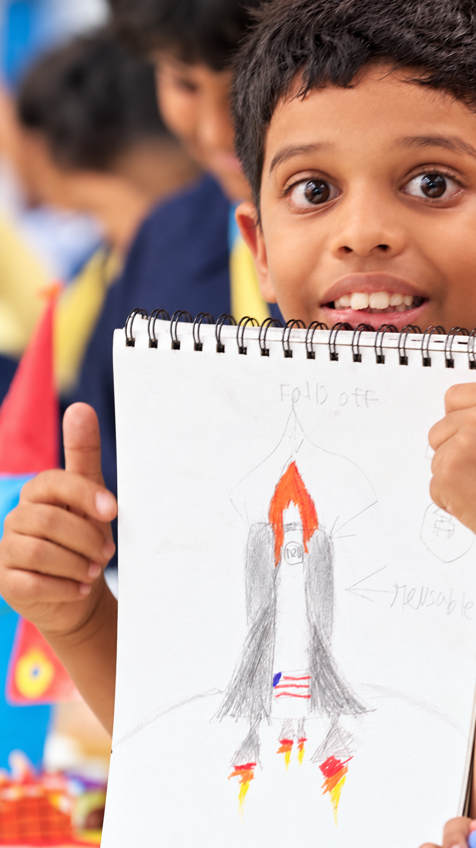 Smiling student showing a rocket drawing and giving a thumbs-up at The Pupil International School, Chennai.