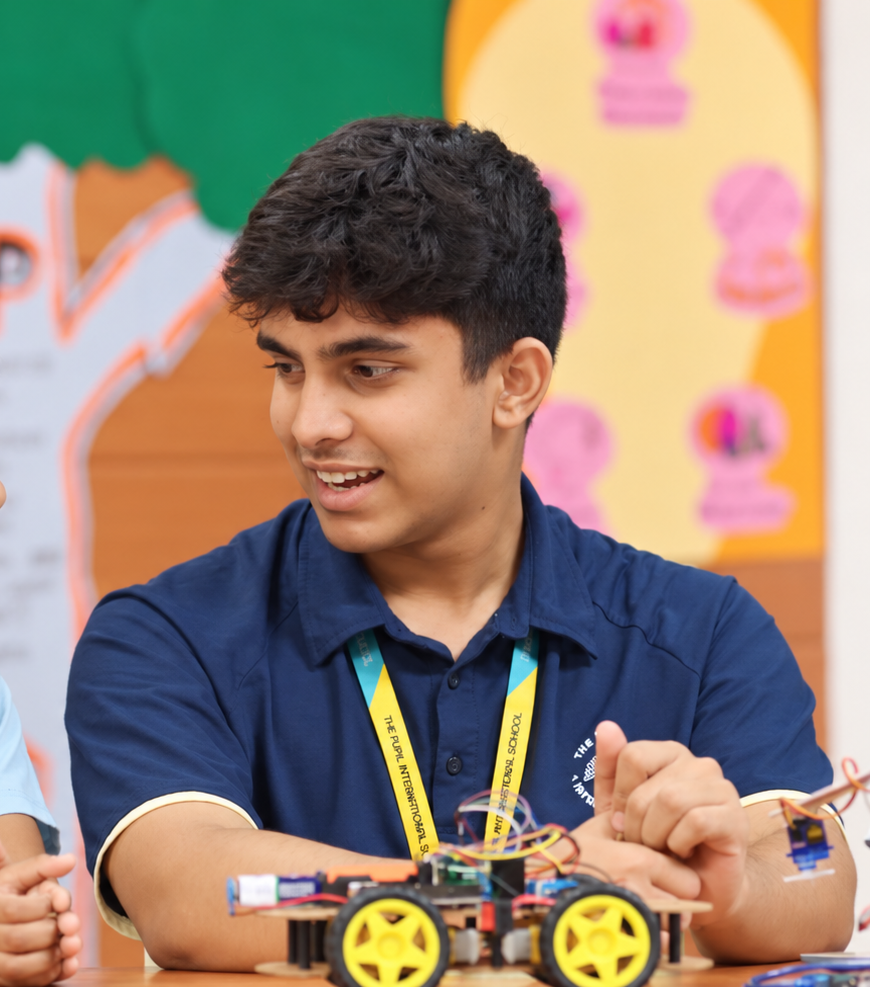Younger and older students sharing a robotics activity with a robot car at The Pupil International School, Chennai.